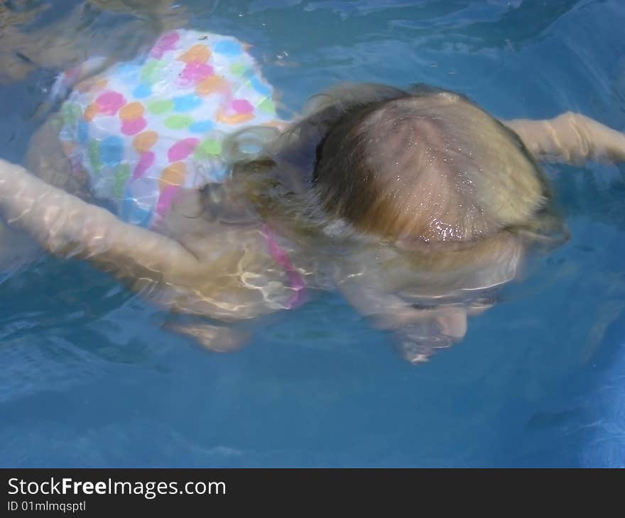 A young girl mostly under the water in a swimming pool or hot tub. 3 years old There is no raw file for this photo. A young girl mostly under the water in a swimming pool or hot tub. 3 years old There is no raw file for this photo.