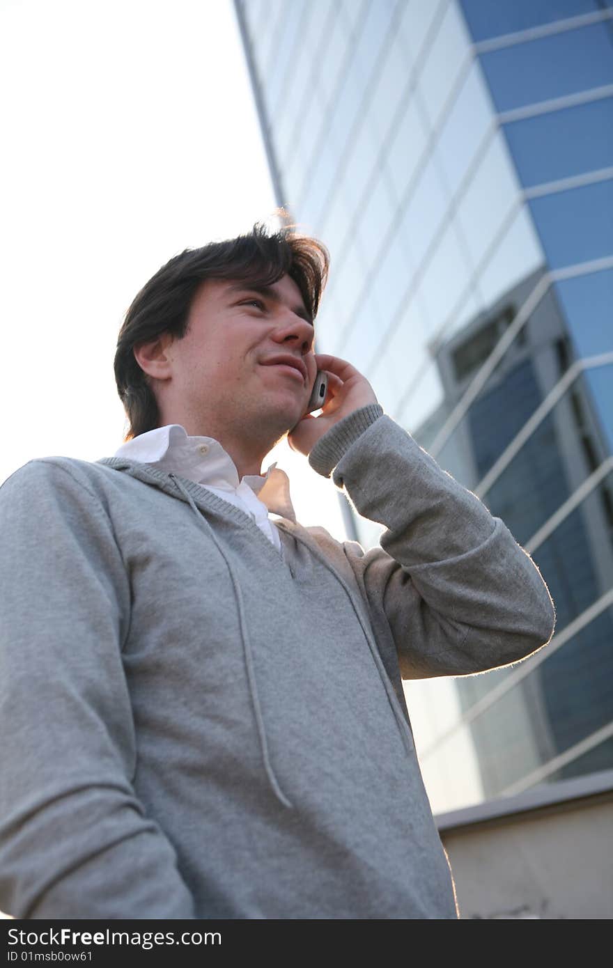 A man talking on a cell phone against the backdrop of a modern building. A man talking on a cell phone against the backdrop of a modern building