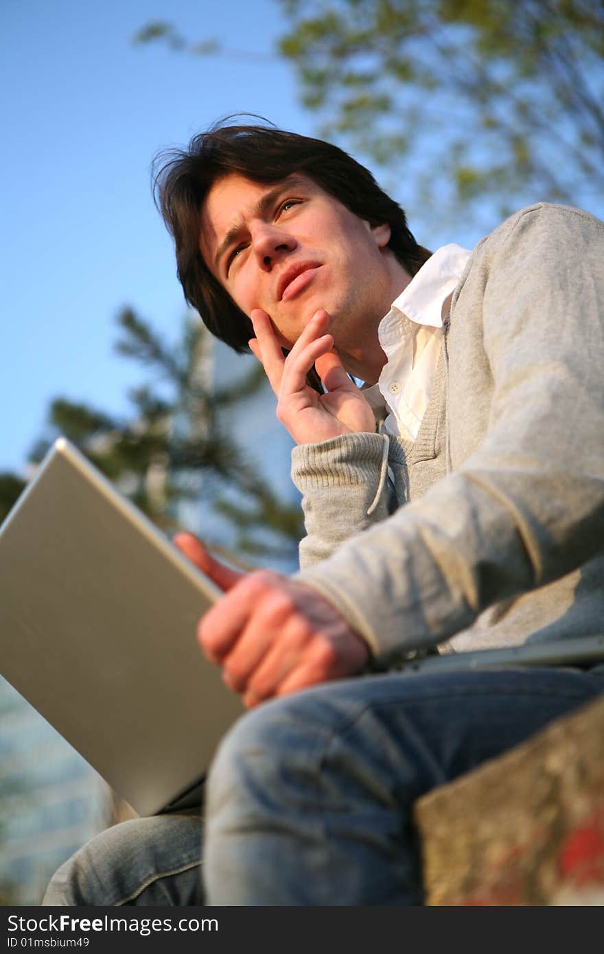 Young man working on a laptop outside. Young man working on a laptop outside.