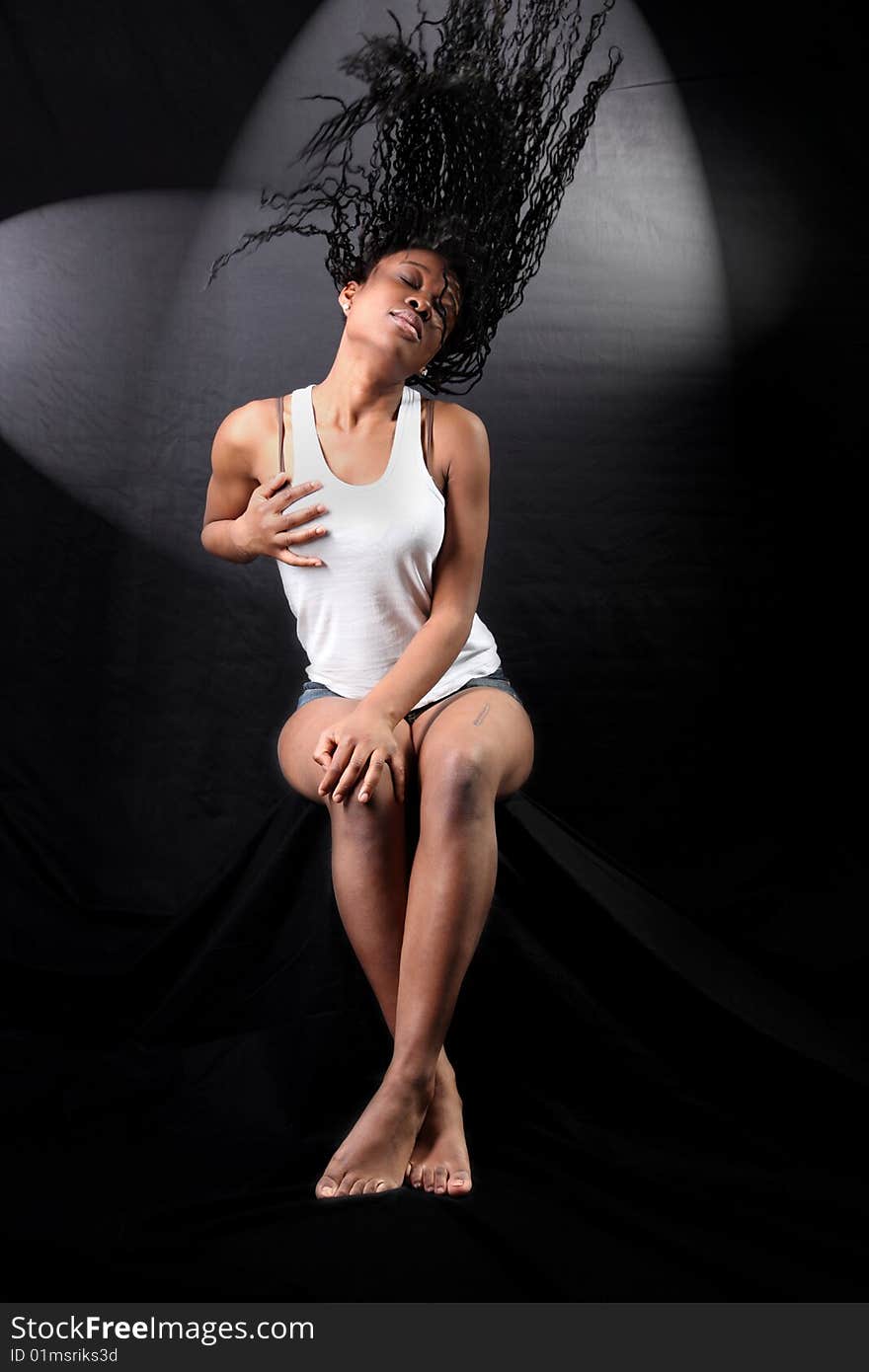 Wind - lovely young afro-american woman with long flapping hairs against black background