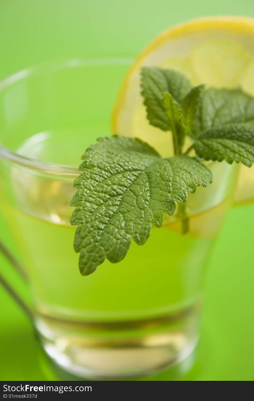 Herb tea with lemon on green table