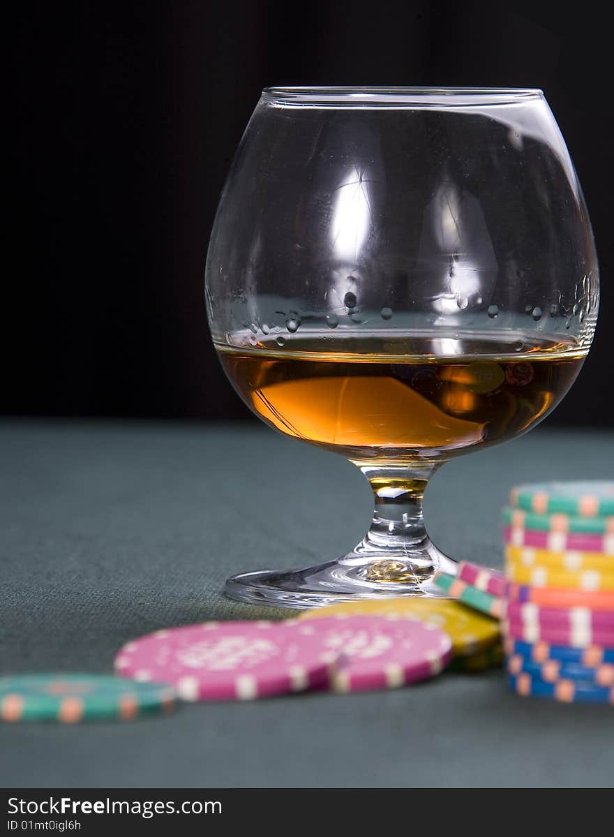 Glass with cognac and chips for a game in a casino. Glass with cognac and chips for a game in a casino