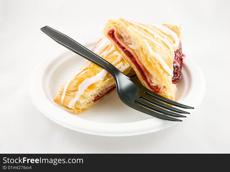 Cherry danish with black fork on a white plate and white background. Cherry danish with black fork on a white plate and white background