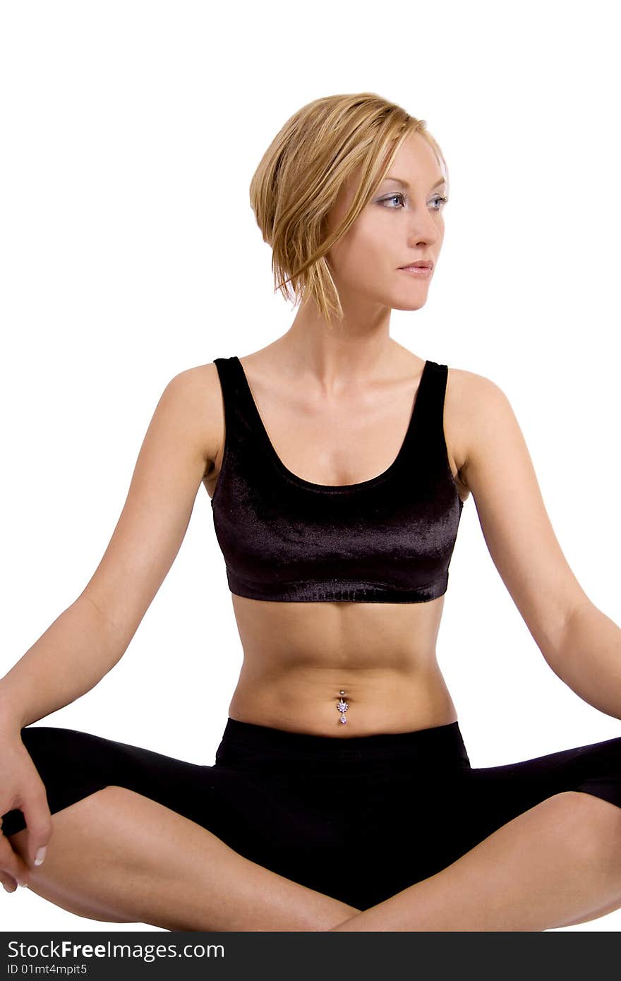 A blond young woman in a fitness outfit is sitting in a lotus position doing yoga. A blond young woman in a fitness outfit is sitting in a lotus position doing yoga