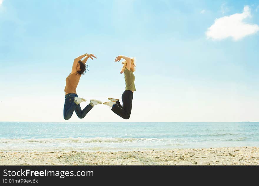 Happy young women jumping on the beach. Happy young women jumping on the beach