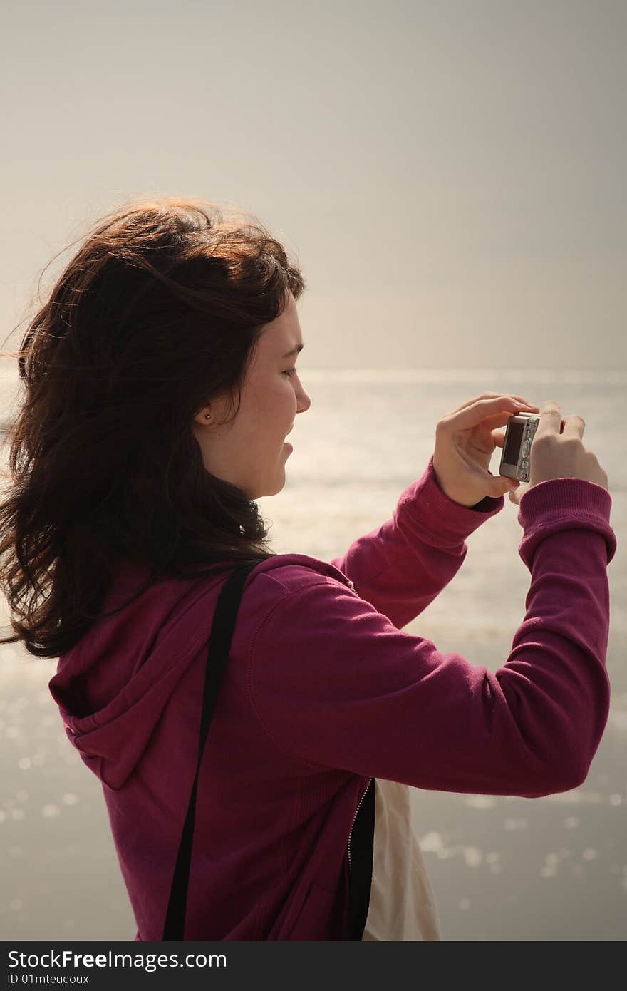 Teen girl taking photos on the beach