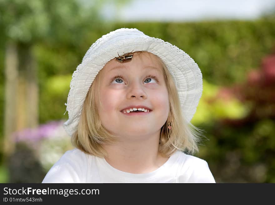 Young girl is watching a chafer beetle which is crawling on her hat. Young girl is watching a chafer beetle which is crawling on her hat