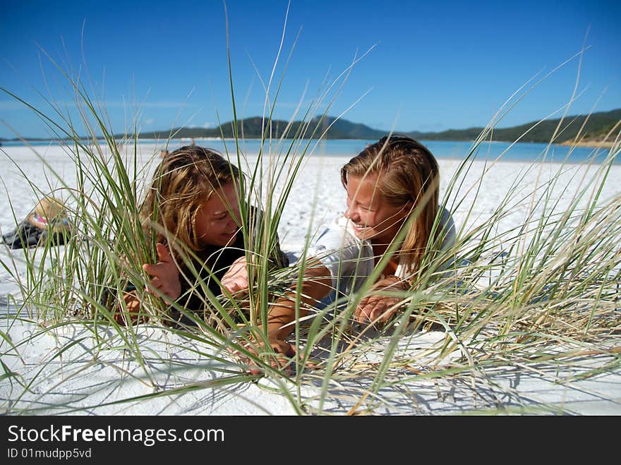 Two young girls hiding behind grass on beach