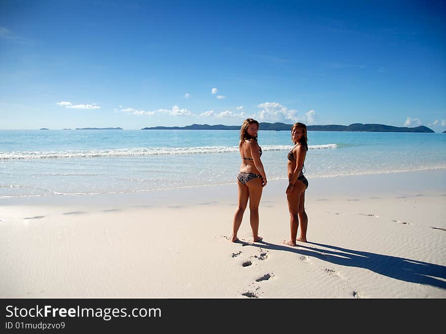 Two Young Girls Standing By Paradise Ocean