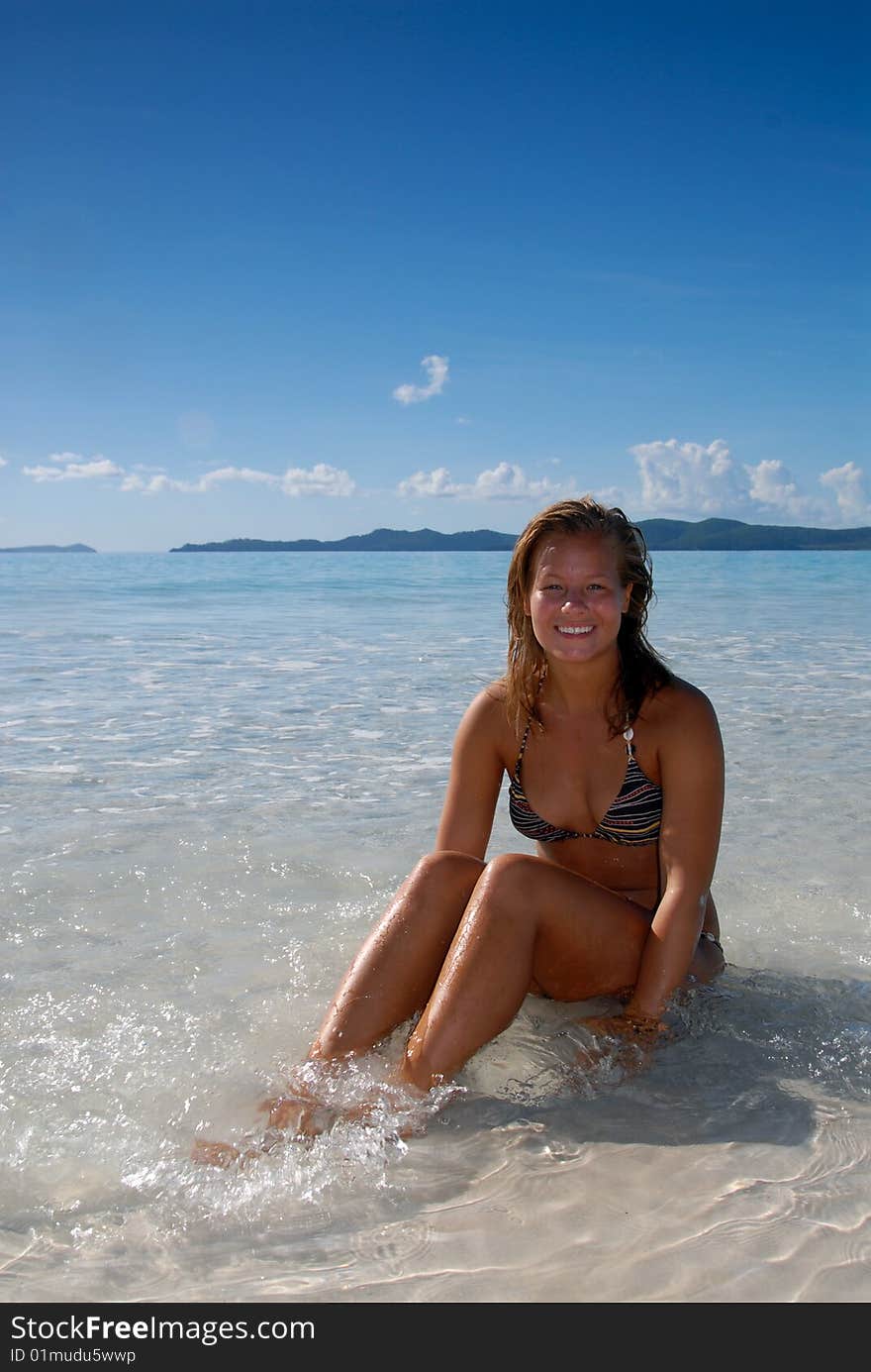 Cute young girl sitting in blue water at paradise beach. Cute young girl sitting in blue water at paradise beach