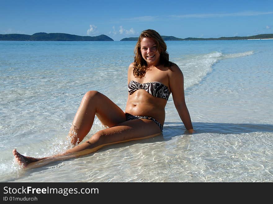 Cute young girl sitting in blue water at paradise beach. Cute young girl sitting in blue water at paradise beach