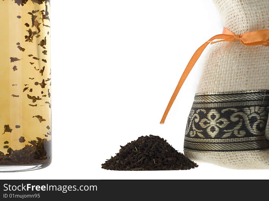 A handful of tea, bag and a glass on a white background.