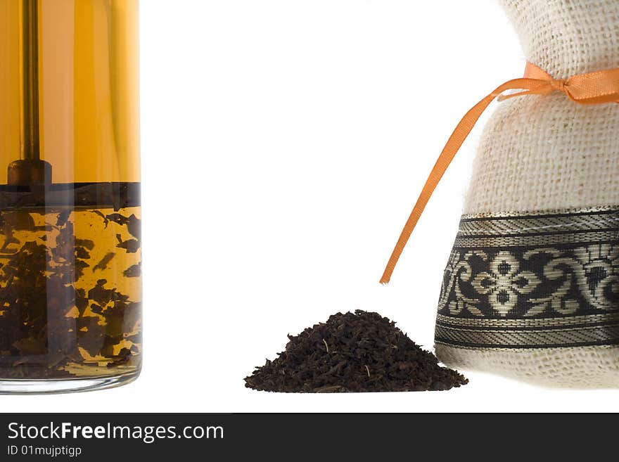 A handful of tea, bag and a glass on a white background.