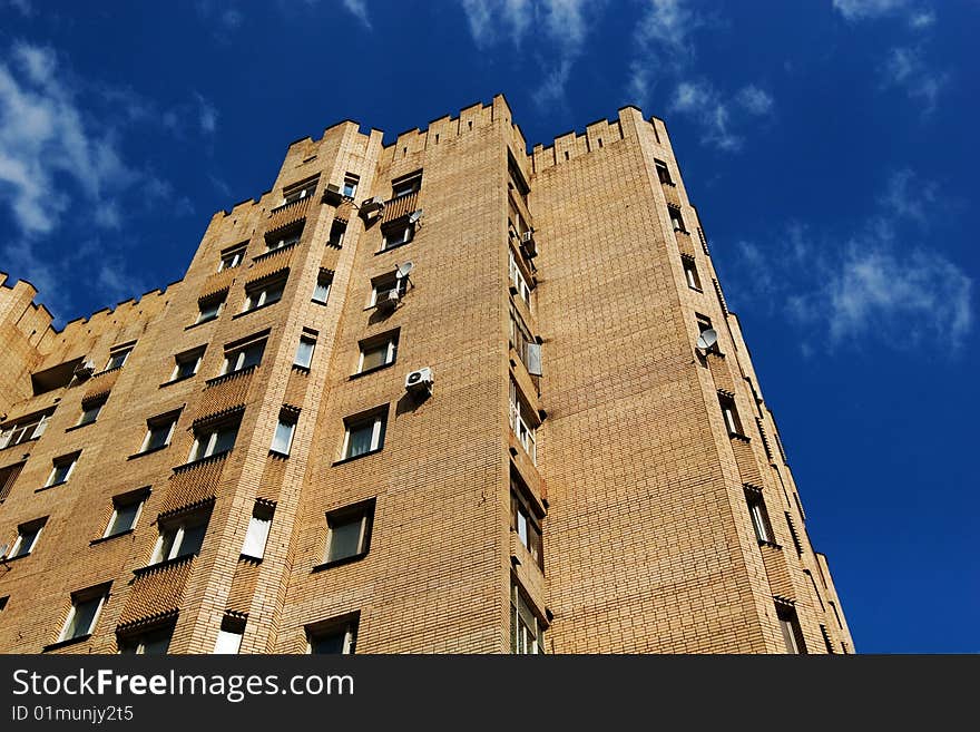 City fortress: yellow multistory brick building on blue sky background