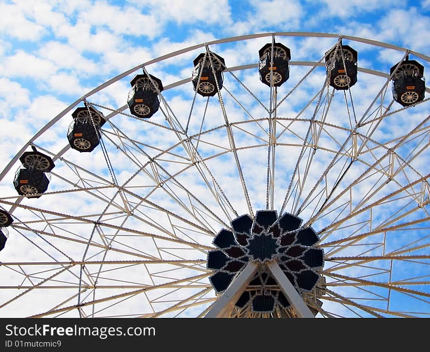 Circling a blue sky full of fluffy white clouds in a ferris wheel.