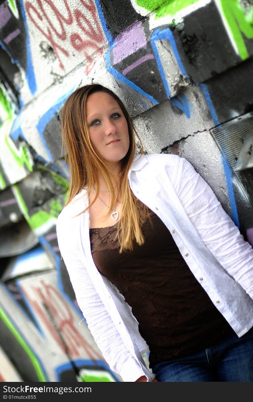 A young woman standing next to a graffiti wall. A young woman standing next to a graffiti wall