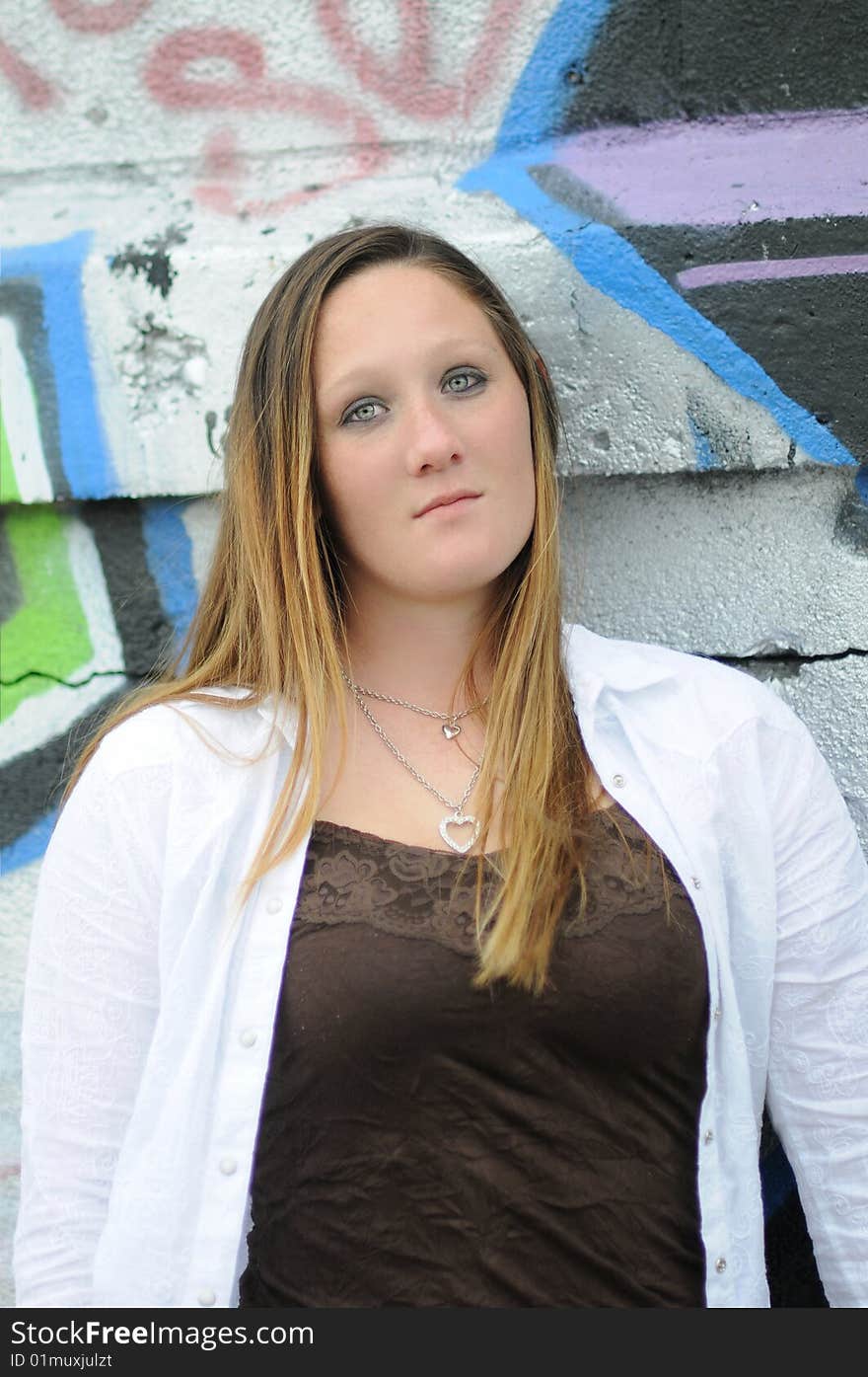 A young woman standing next to a graffiti wall. A young woman standing next to a graffiti wall