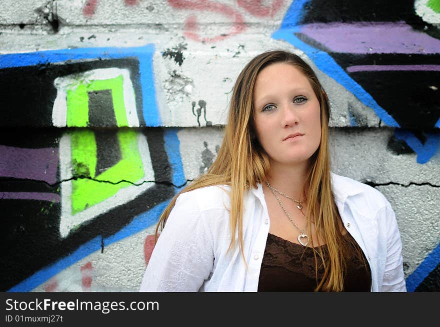 A young woman standing next to a graffiti wall. A young woman standing next to a graffiti wall