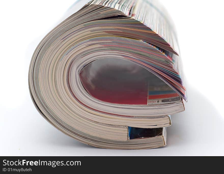 Pile of glossy magazines is curtailed into  roll isolated on white background