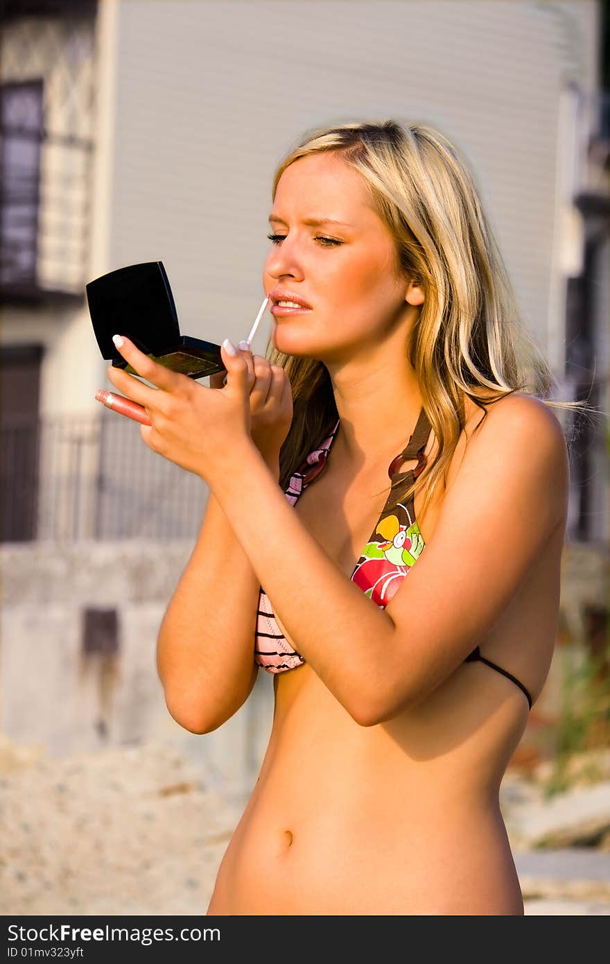 Pretty woman applying makeup in a beach