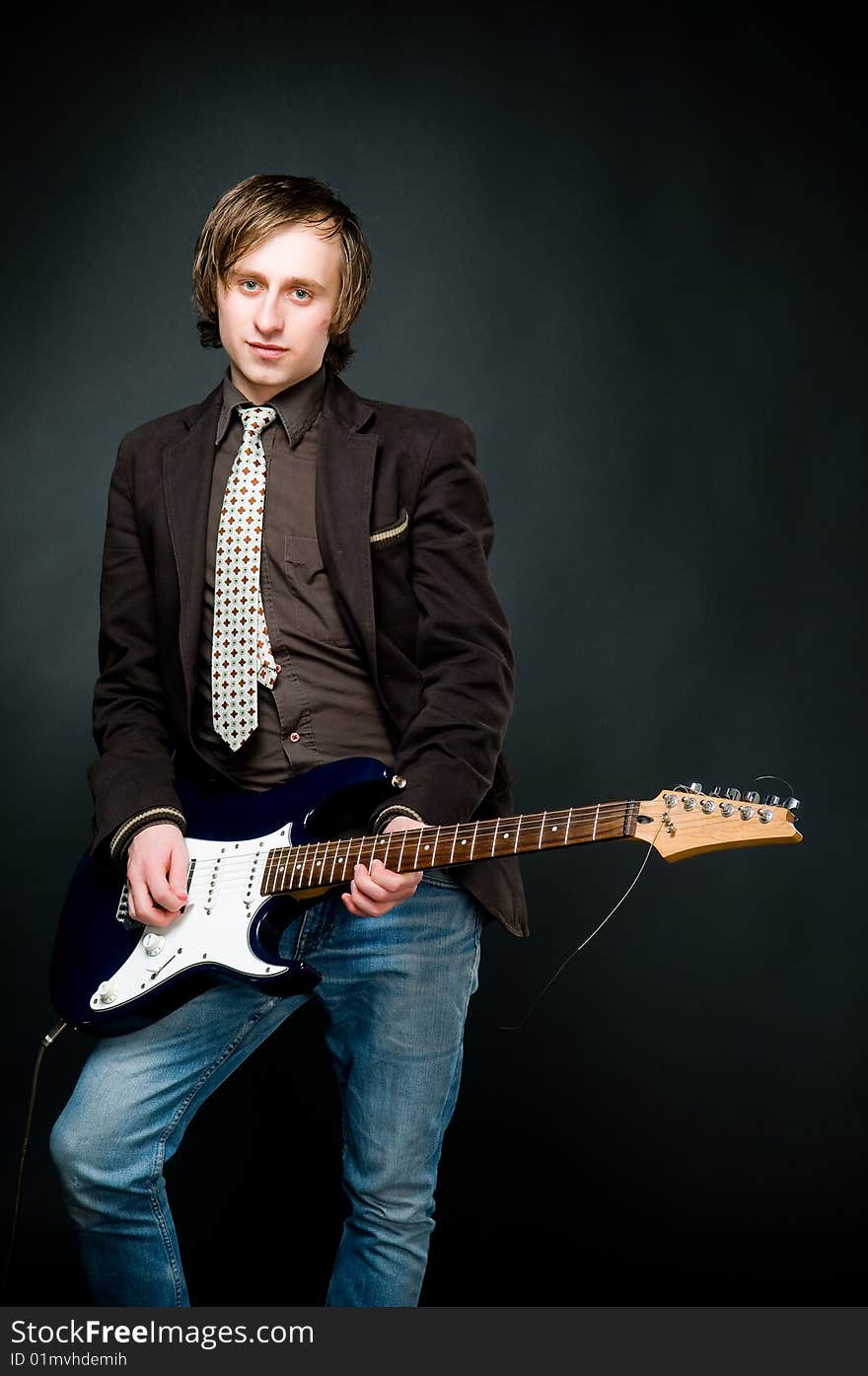 Young man playing electro guitar, studio shot