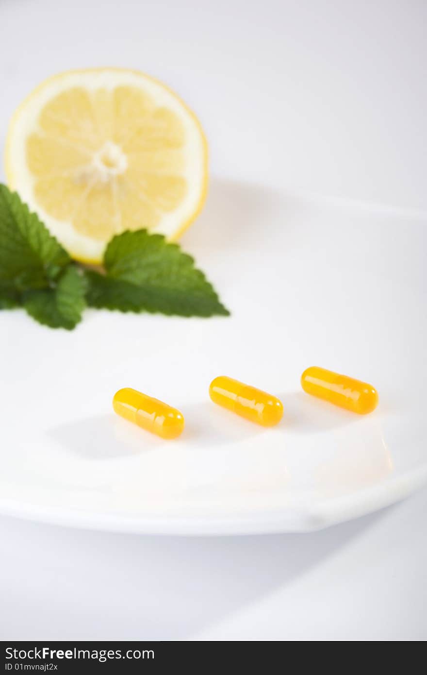 Yellow pills on white plate with lemon