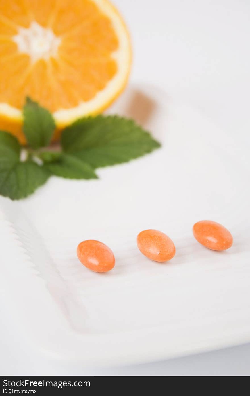 Yellow pills on white plate with orange