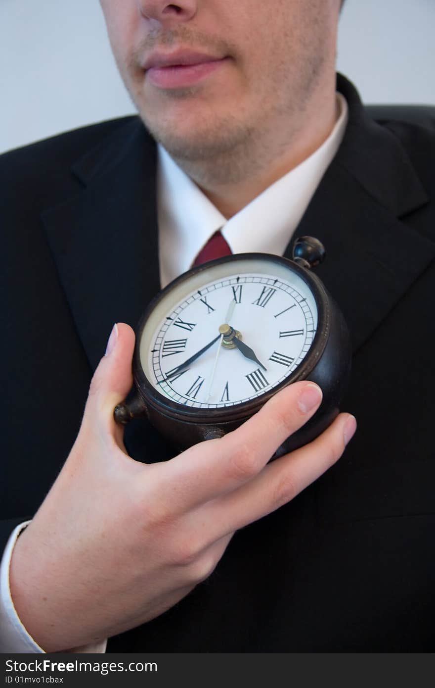 A young attractive businessman holds time in his hand.