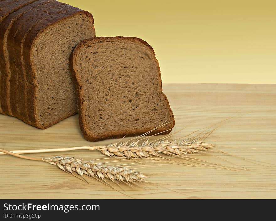 Wheat ears and sliced bread on desk