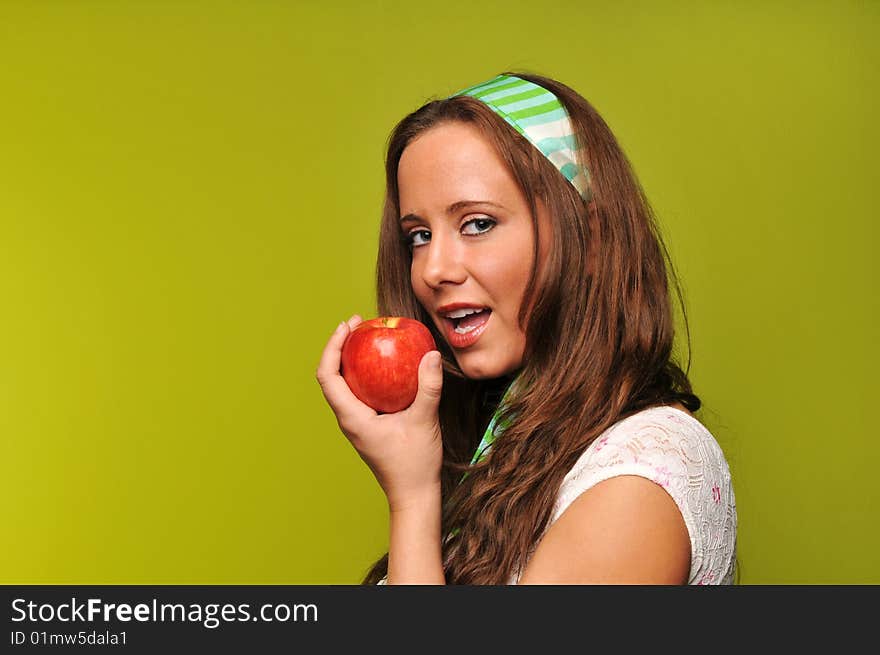 Brunette holding apple against a green background