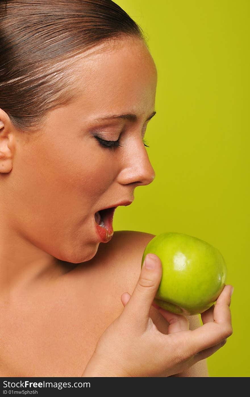 Brunette holding apple against a green background