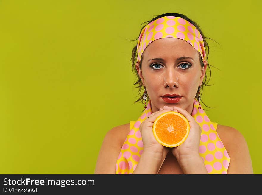 Brunette holding orange against a green background