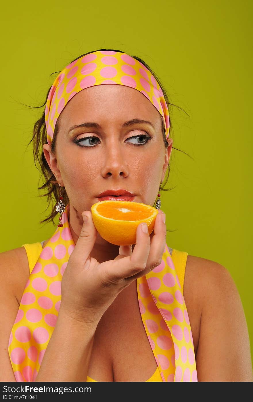 Young woman fashion model holding orange isolated on a green background. Young woman fashion model holding orange isolated on a green background