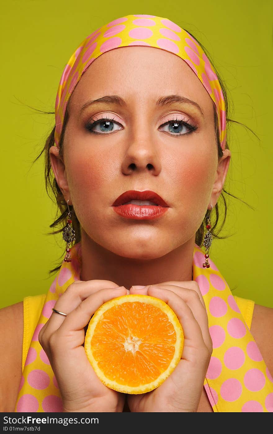 Brunette holding orange against a green background