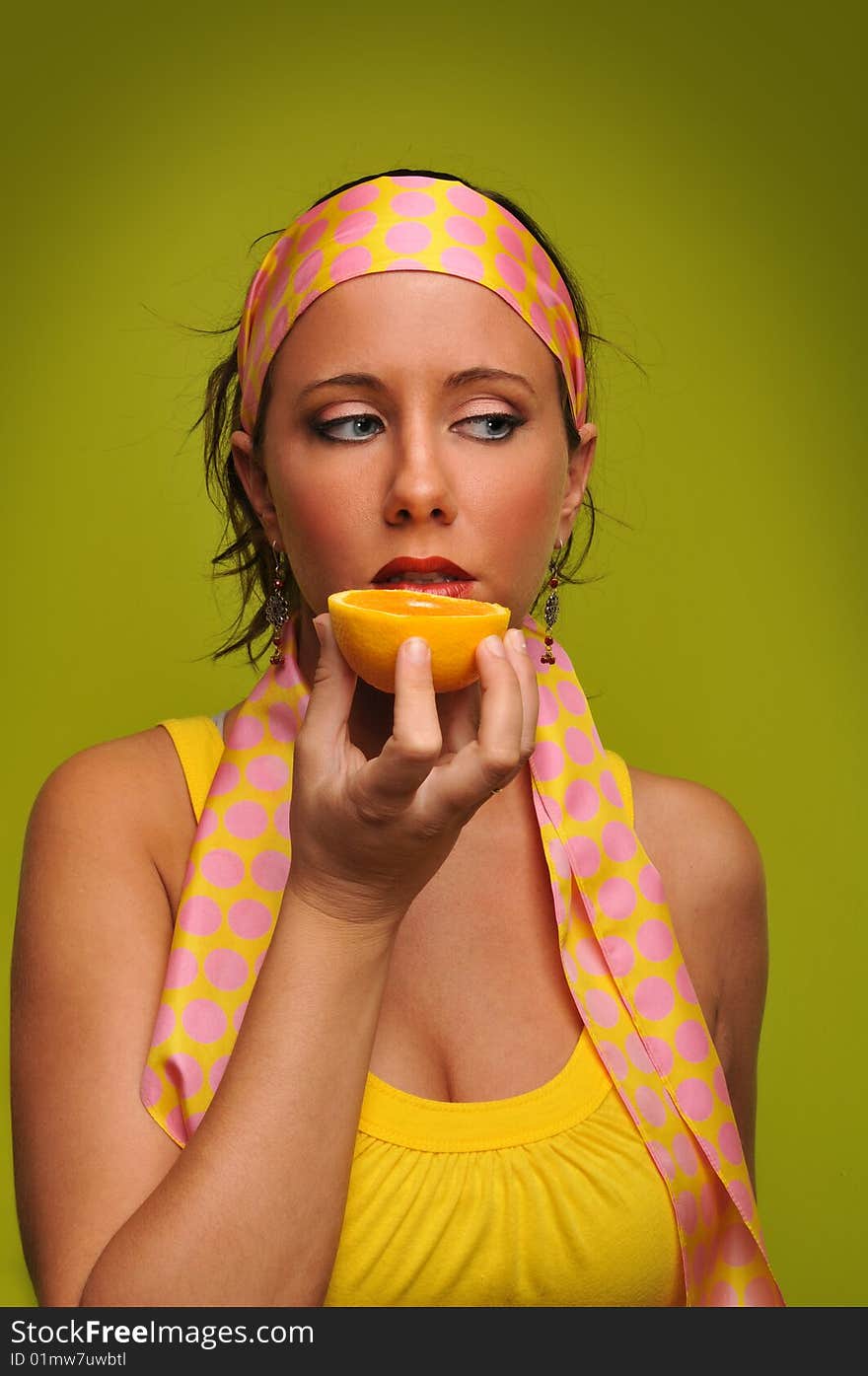 Young woman fashion model holding orange isolated on a green background. Young woman fashion model holding orange isolated on a green background