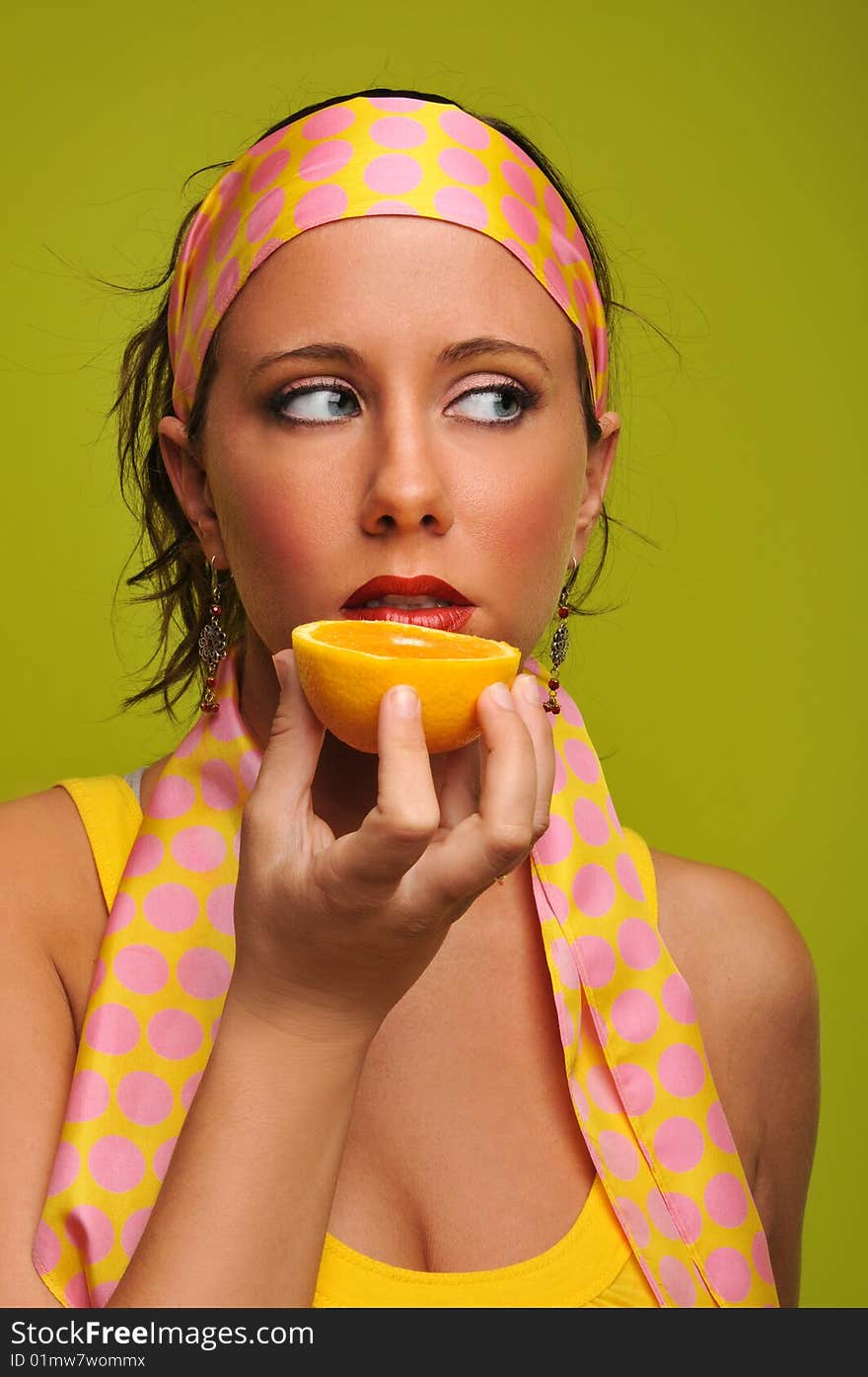 Young woman fashion model holding orange isolated on a green background. Young woman fashion model holding orange isolated on a green background