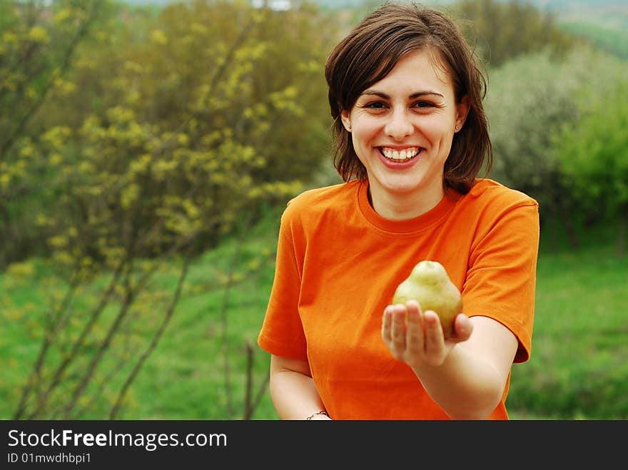 Pretty girl in orange shirt holding a pear in hand. Pretty girl in orange shirt holding a pear in hand