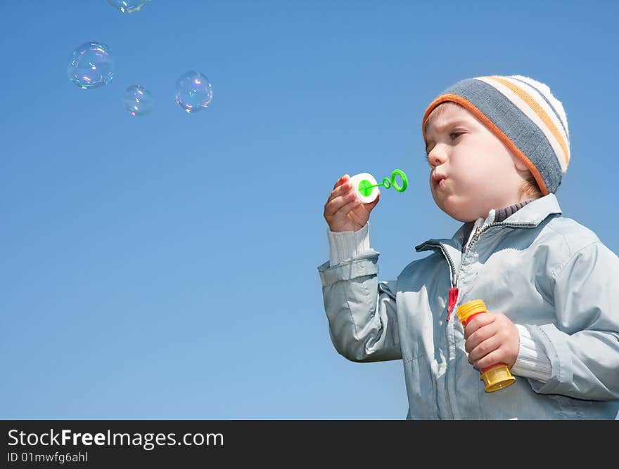 Boy blowing bubbles under blue sky