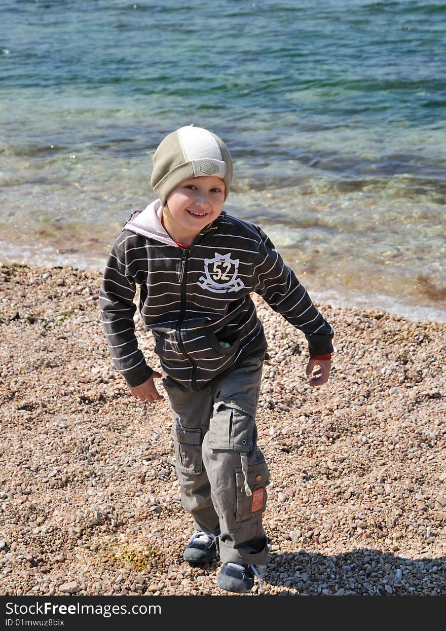 Little boy is jumping on the beach in springtime, he is smiling and happy. Little boy is jumping on the beach in springtime, he is smiling and happy