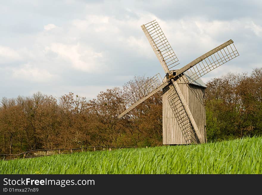 The old windmill to stand on a green field near wood