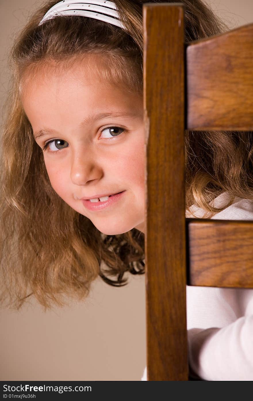 Cute little girl sitting on a chair looking over her shoulder. Cute little girl sitting on a chair looking over her shoulder