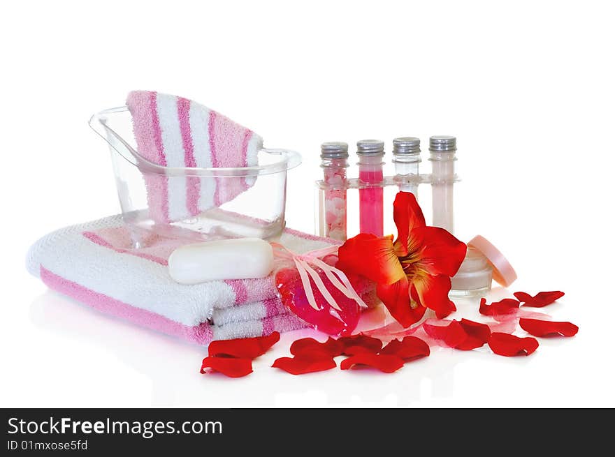 Spa essentials surrounded by rose petals on white background, reflective surface. Spa essentials surrounded by rose petals on white background, reflective surface