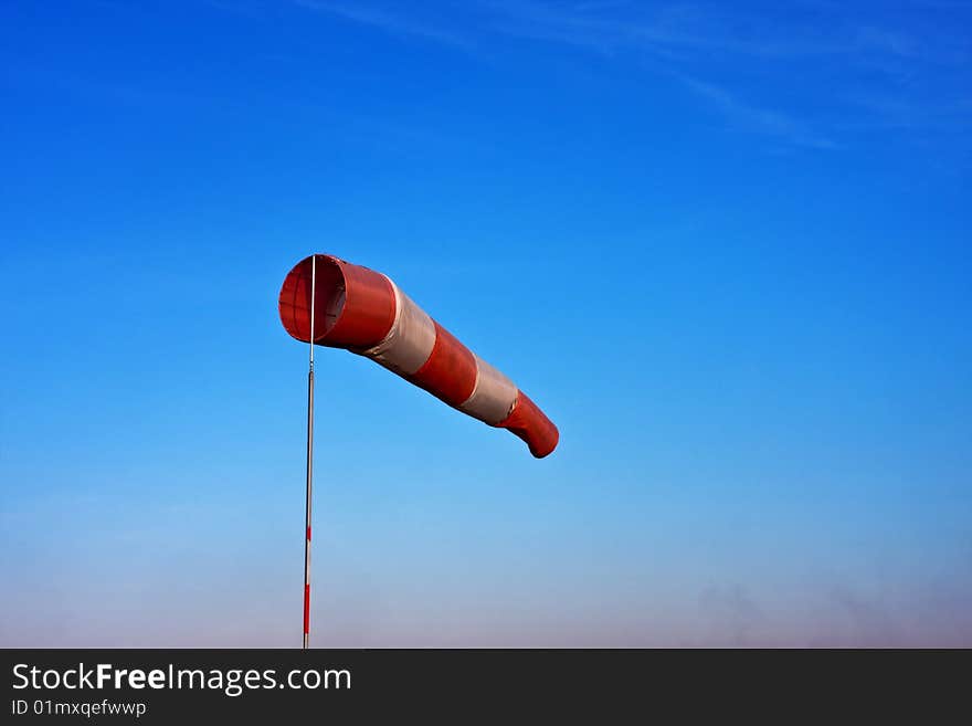 Windsock in airfield showing wind strength on blue sky background.