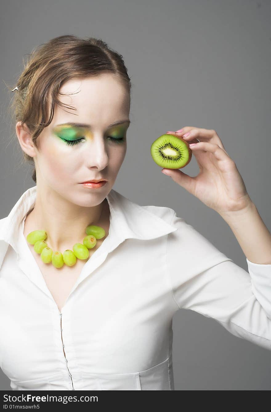 Portrait of young woman with pieces of kiwi