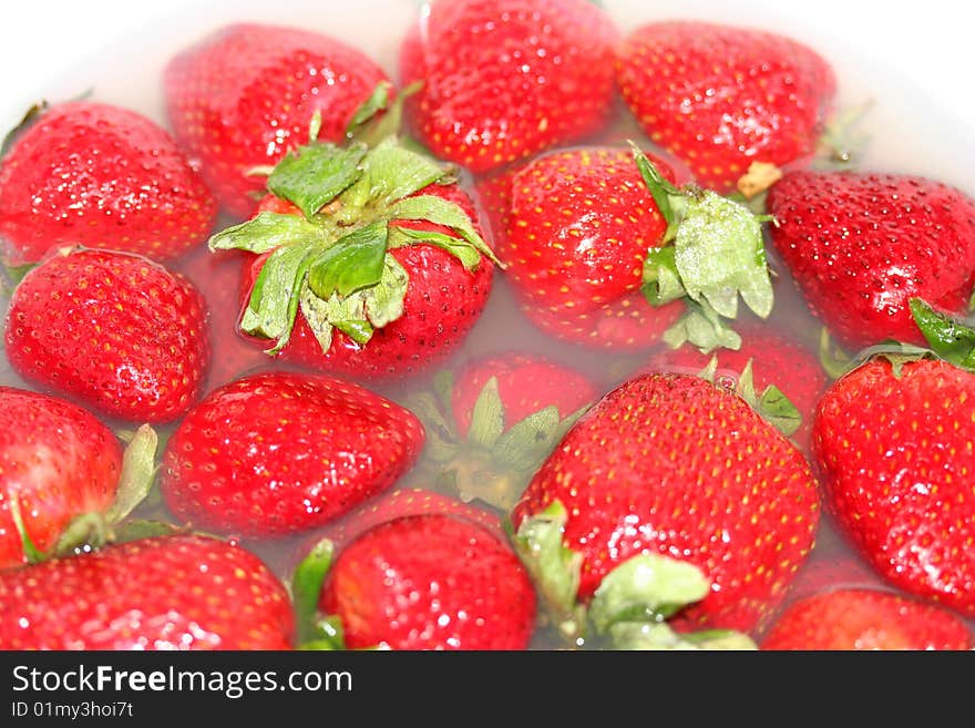 A macro shot of strawberries cleaning in a fruit wash. A macro shot of strawberries cleaning in a fruit wash.