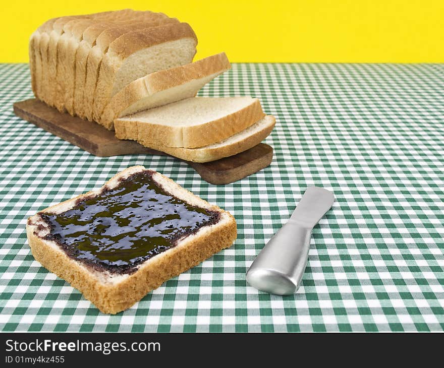 A slice of bread spread with jam beside the loaf of bread. A slice of bread spread with jam beside the loaf of bread.