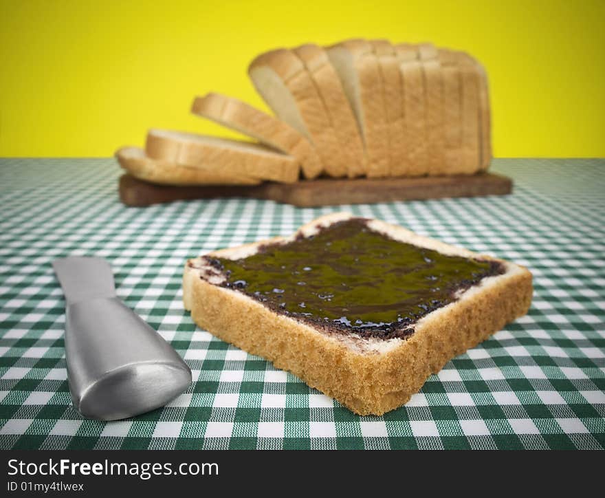 A slice of bread spread with jam. Loaf of bread on the background. A slice of bread spread with jam. Loaf of bread on the background.