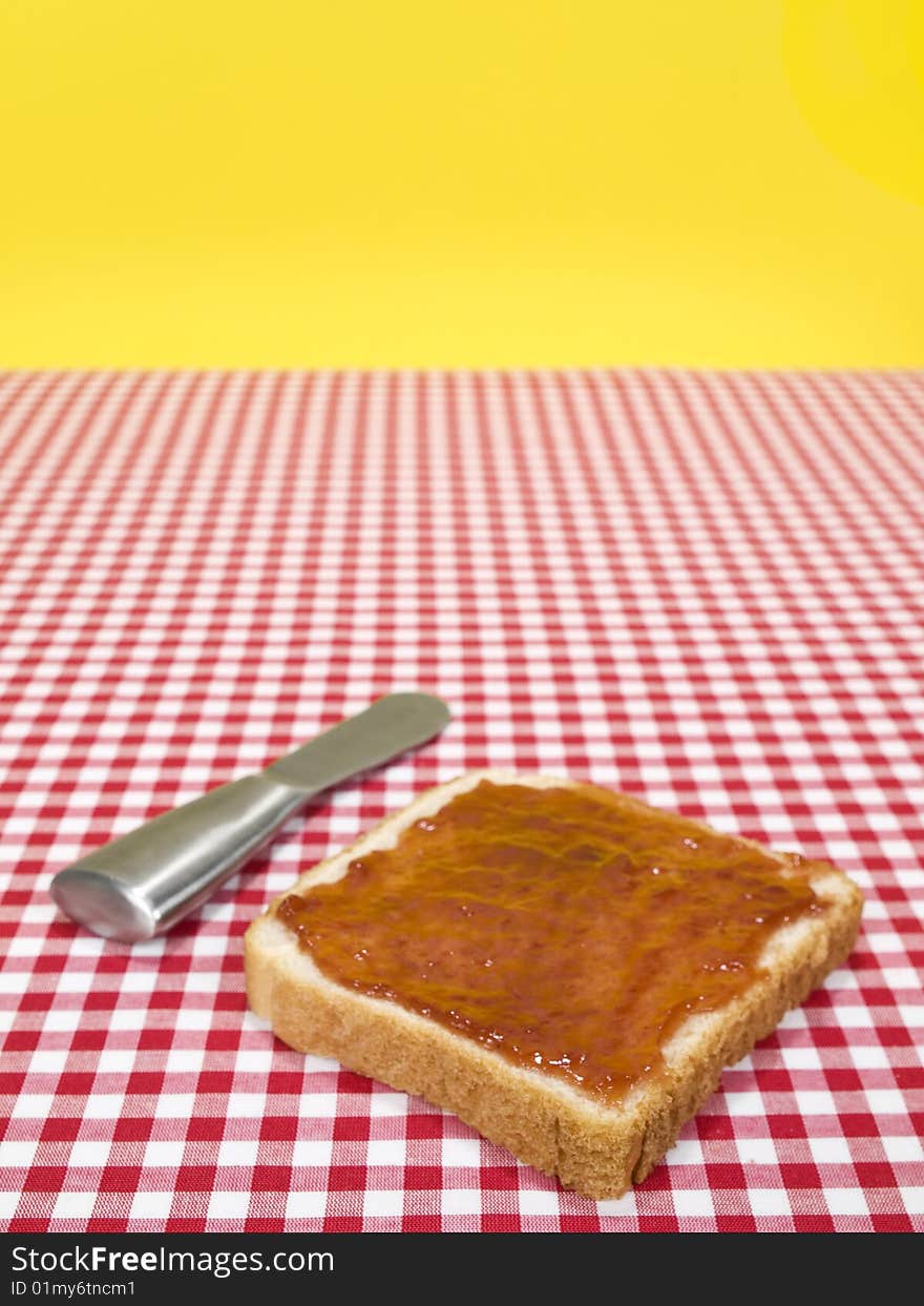 A slice of bread spread with jam and a knife over the table. A slice of bread spread with jam and a knife over the table.