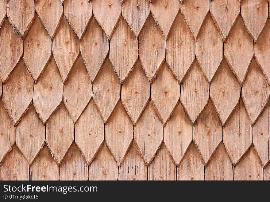 A part of a roof of an old house made of brown wooden tiles