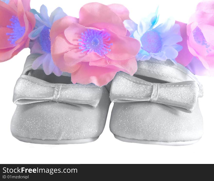 Children's silver shoes with bows and a wreath from colours close up. Children's silver shoes with bows and a wreath from colours close up